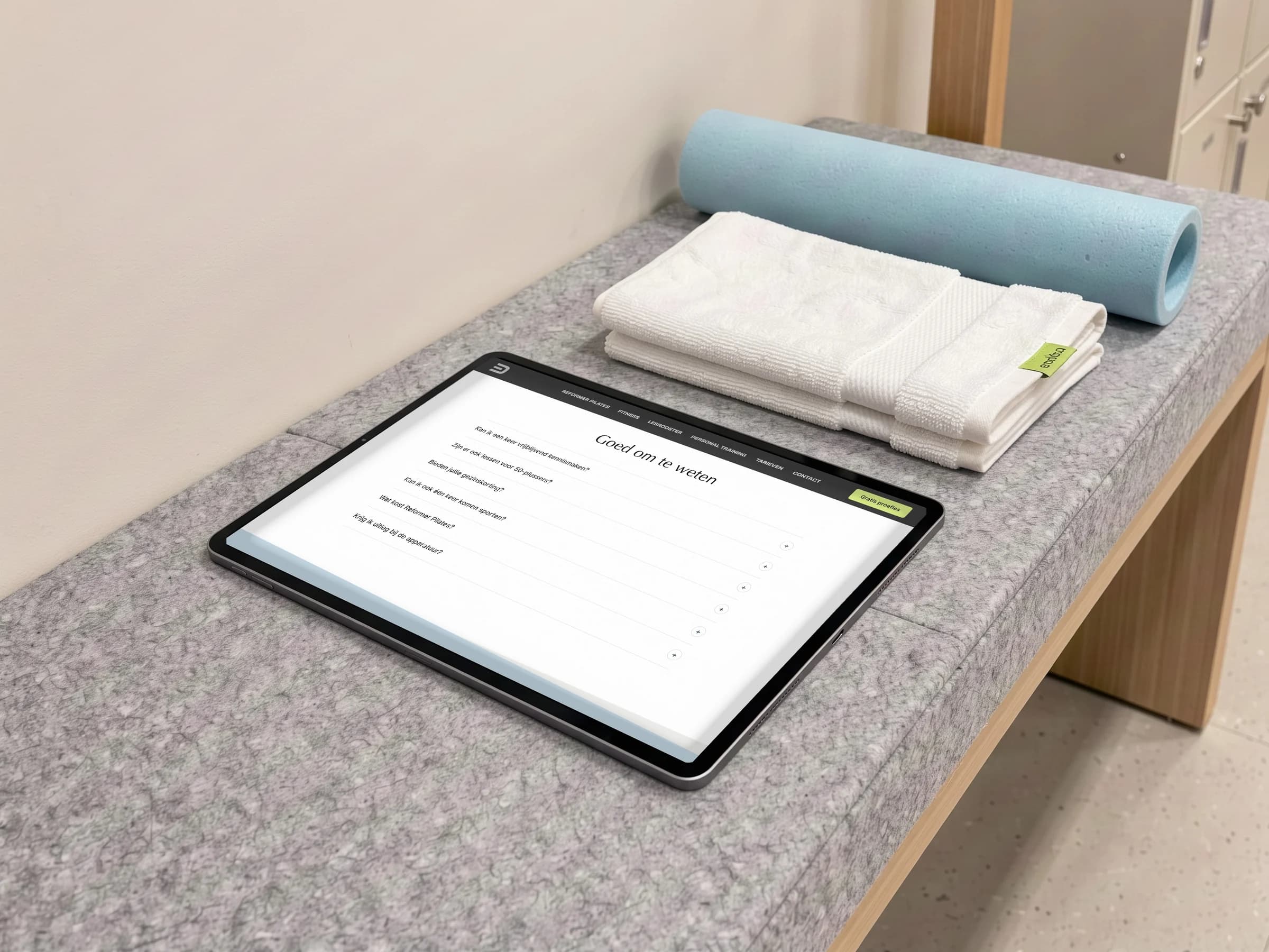 De veelgestelde vragen van De Kloek Fitness op een tablet op een bank, met een handdoek en een ijsblauwe foamroller