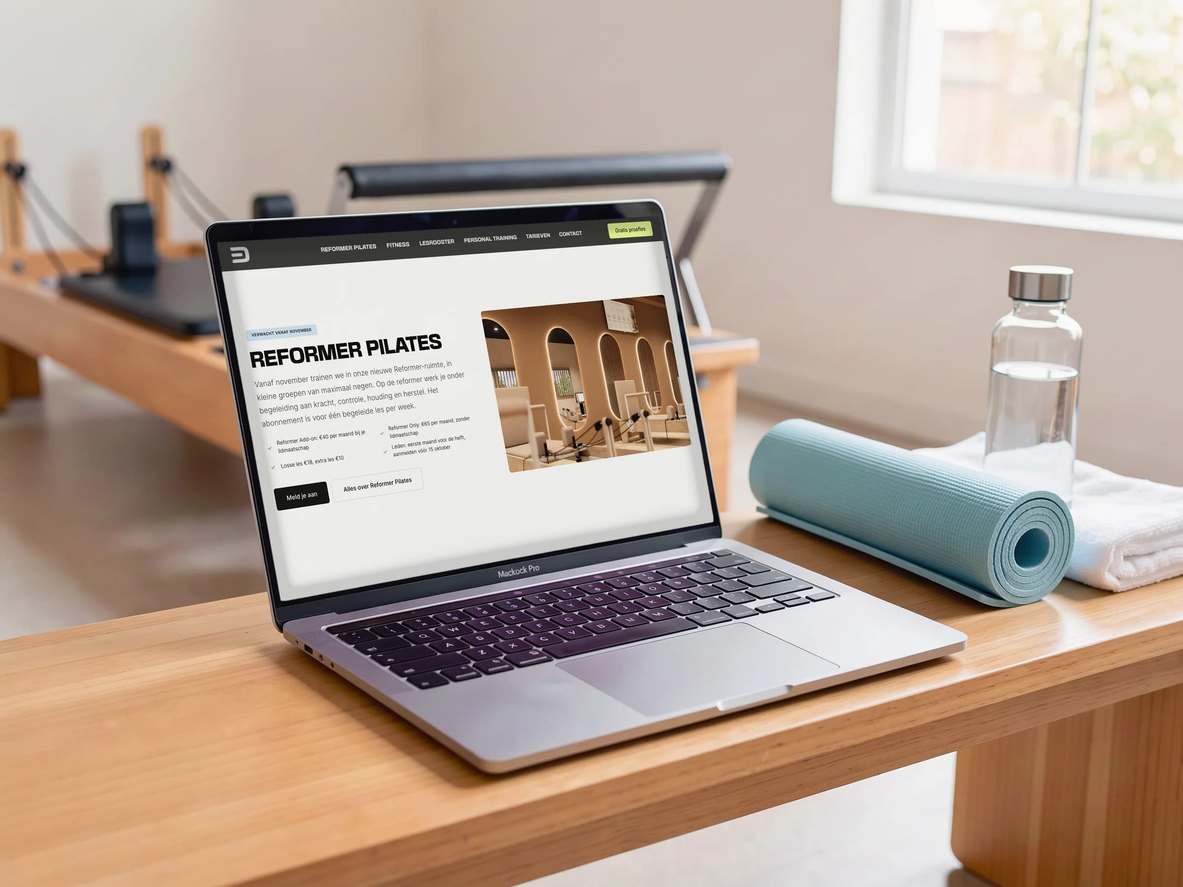 De Reformer Pilates-sectie van De Kloek Fitness op een laptop in een lichte pilatesstudio, naast een ijsblauwe yogamat