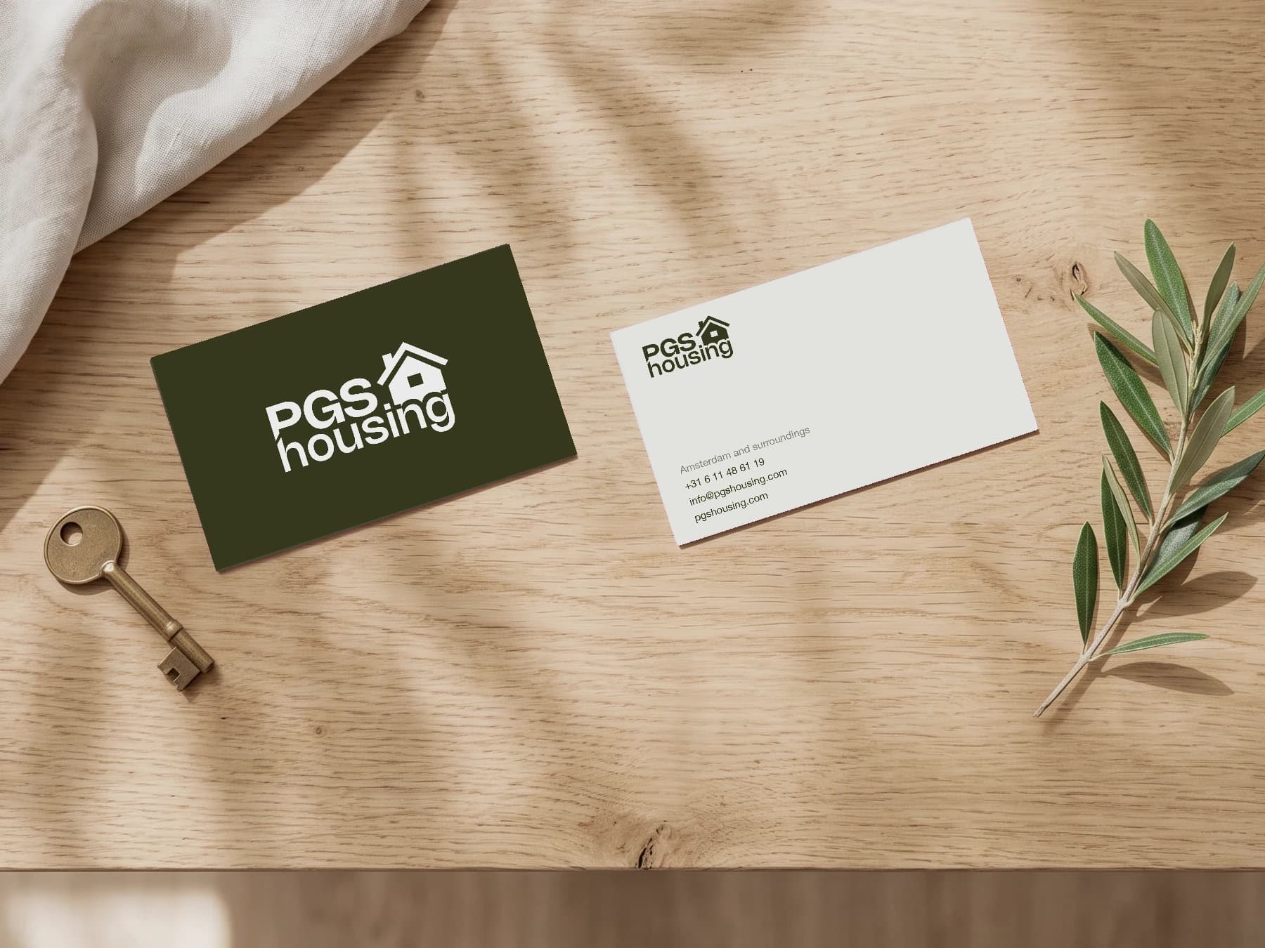Visitekaartje van PGS Housing, voor- en achterkant, op een eiken tafel