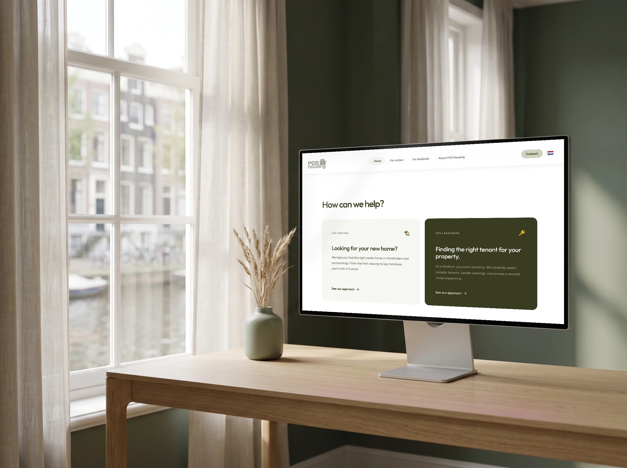 De Engelse homepage van PGS Housing op een desktopscherm voor een raam met uitzicht op een gracht